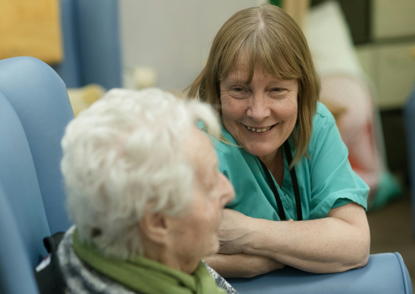 A nurse smiling as she talks with an older woman